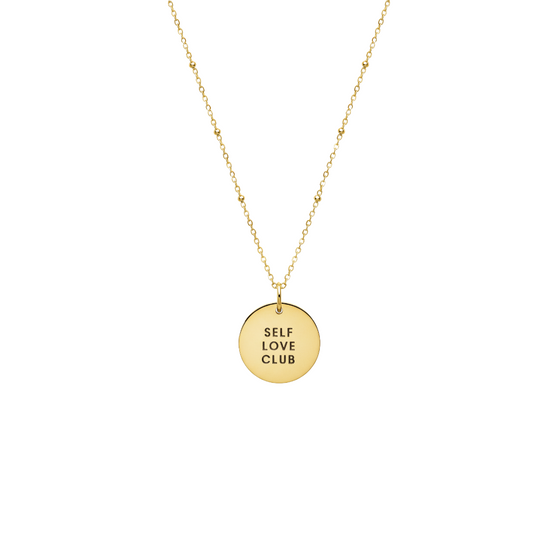 A close-up of the gold-filled self-love club necklace against a white background.
