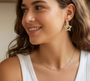 A model wearing long gold earrings with stone stars, an elegant pair of long earrings with a sparkling stone star pendant, made from 18-karat gold-plated stainless steel.