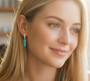 A model wearing gold and turquoise Huggies drop earrings, with striking turquoise pendants on elegant gold Huggies hoops.