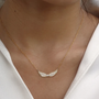 Wings Of An Angel Necklace by Keira K in gold on a model's neck