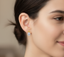 A model wearing Morning Dew Drops Studs earrings in 18-karat gold-plated sterling silver. They are delicate and feature moissanite gemstones.