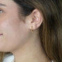A model showcasing elegant 18k gold-filled stud earrings featuring a radiant sunray burst design.