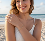 Model wearing an 18K gold paperclip chain bracelet with sparkling Moissanites accents, set against a beach background.
