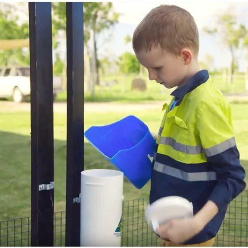Child filling a Dine-A-Chook Large Chicken Feeder from a feed scoop
