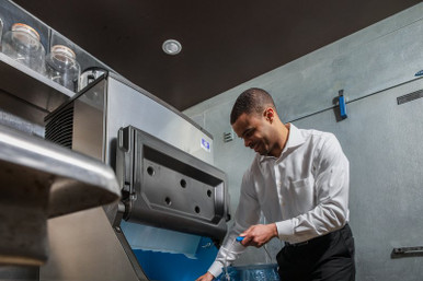 Commercial ice machine technician performing a maintenance check on a Manitowoc unit