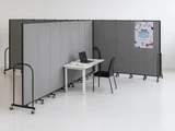 Gray mobile partition panels creating a private desk workspace with a table, chair, and laptop.