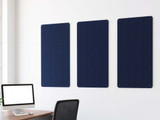 Three navy blue acoustic wall panels mounted above a desk in a modern office.