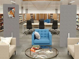 Library seating area with a gray freestanding divider displaying colorful event flyers between tables and bookshelves.