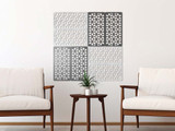 Four geometric decorative wall panels above two armchairs and a small table with a potted plant.