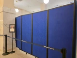 Blue wheeled divider panels forming a temporary barrier inside a train station concourse.