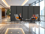 Two people seated in a modern lobby, partially screened by a large black wheeled divider panel.