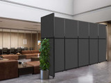 Dark gray freestanding partition wall with a black frame dividing a lobby seating area, with a potted plant in front.
