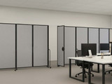 Modern office with gray rolling partition panels dividing shared desks with computers and task chairs.