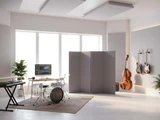 Modern music studio with instruments and a gray freestanding acoustic divider near a drum set.