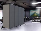 Gray rolling partition panels dividing a modern office workspace with desks, chairs, and a large wall artwork.