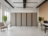 Modern office space with a row of beige rolling partition panels dividing the room, flanked by chairs, desks, and indoor plants.