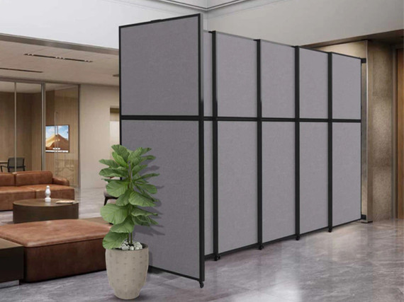 Gray freestanding office partition wall with black frame, positioned in a lobby seating area with a potted plant nearby.