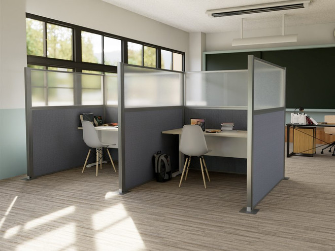 Office workstations created with fabric and frosted partition panels, featuring desks, chairs, and backpacks near large windows.