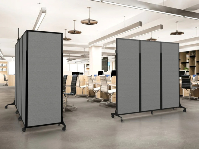 Modern open office with gray rolling partition panels dividing rows of workstations and office chairs.