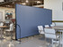 Cafe seating area divided by a long blue fabric privacy screen on wheels.