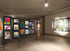 Art gallery with rolling display panels showcasing framed artwork, arranged in a spacious exhibition hall with overhead lighting.