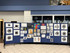 Student artwork displayed on blue rolling partition panels arranged in a school hallway.