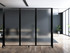 Frosted wheeled divider panels separating areas in a modern office with wood floors and large windows.