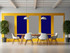 Modern meeting area with a wooden table, white chairs, and colorful acoustic wall panels in yellow, blue, and gray.