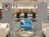 Library seating area with a gray freestanding divider displaying colorful event flyers between tables and bookshelves.