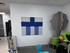 Office wall with blue and gray acoustic art panels, colorful stacked seating, and a tree-shaped panel.