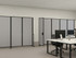 Modern office with gray rolling partition panels dividing shared desks with computers and task chairs.
