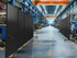 Industrial factory floor with rows of black wheeled divider panels lining a wide production aisle.