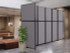 Gray freestanding office partition wall with black frame, positioned in a lobby seating area with a potted plant nearby.