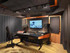 Professional audio mixing studio with a control desk, speakers, monitor screen, and acoustic wall panels.