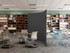 Library study area with bookshelves and tables, divided by a curved gray freestanding partition.