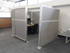 Gray fabric office cubicle with a frosted sliding door opening to a small desk workspace