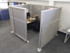 Person working at a desk inside gray fabric office cubicle panels with a frosted sliding partition.