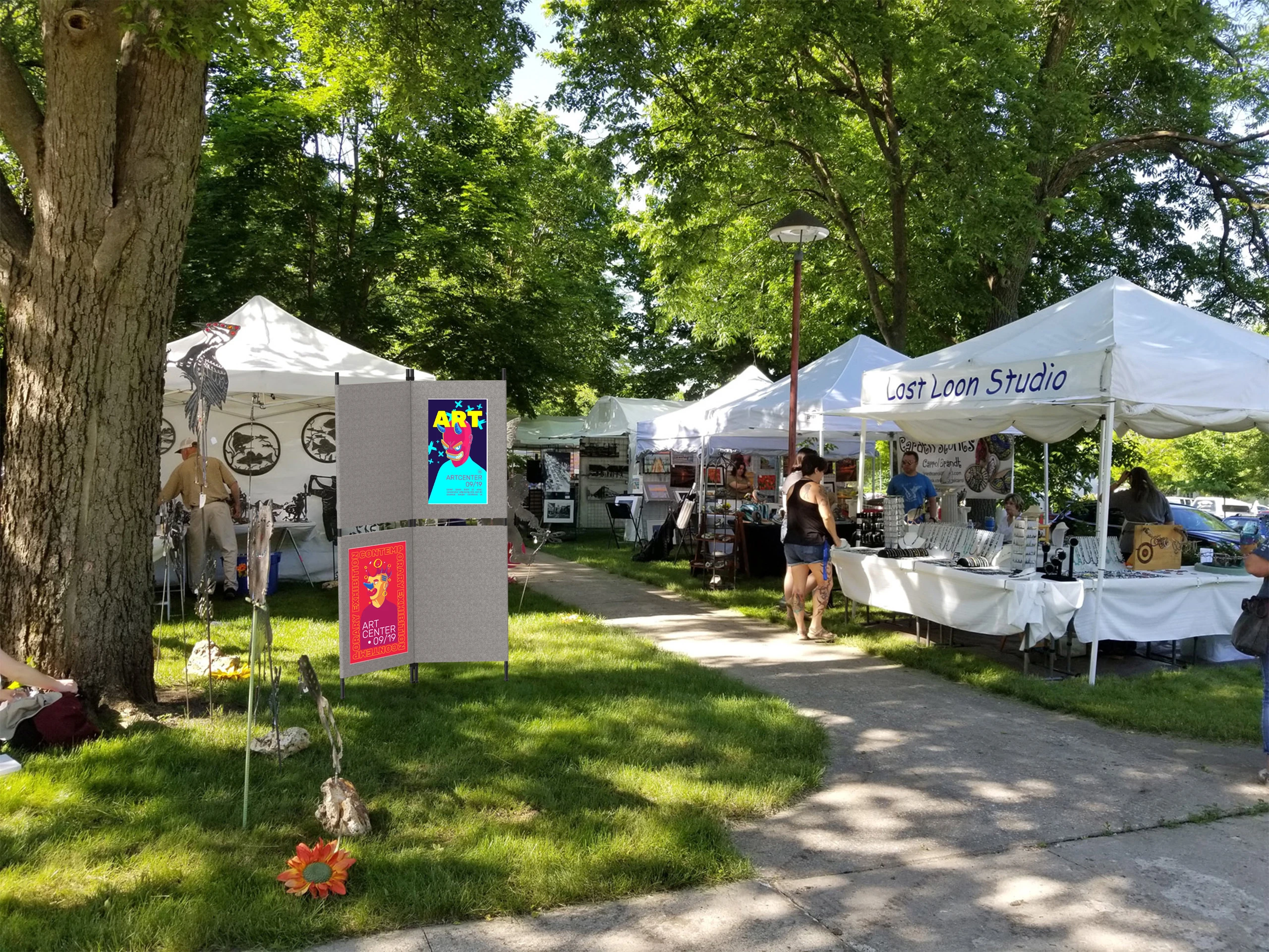 A portable outdoor display board holds event posters at an art fair.