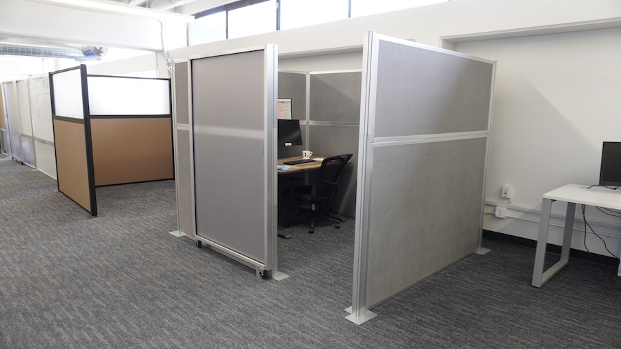 A row of office cubicles, including a kitted version with a sliding door panel.