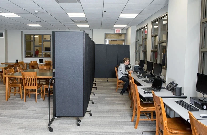 A black room divider in an L-shape provides division between a gaming room and tables and chairs