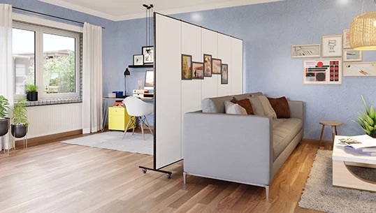 A neutral-colored portable room divider separates a homeschool study area from a residential living room.
