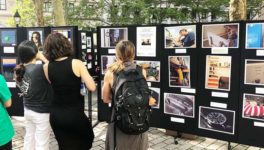 Visitors view artwork hung up on portable display panels at an art show.