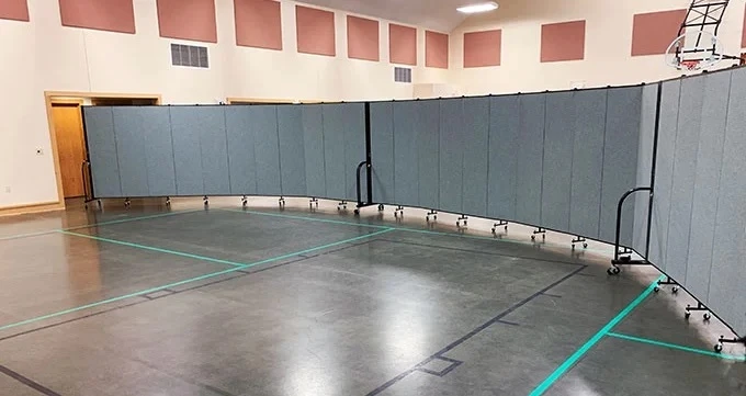 Church room dividers separate a gym into two areas Portable wall divider separates a gymnasium into two classrooms