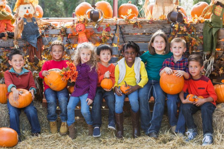 kids at a fall festival holding pumpkins