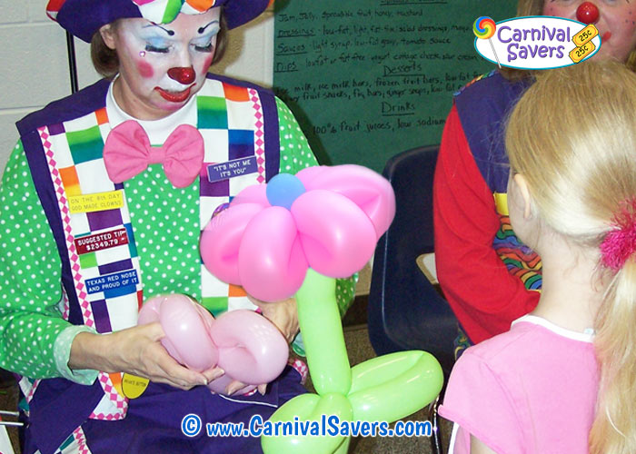 Balloon clown making shaped balloon for child at a carnival