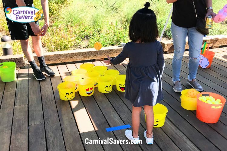 Girl tossing ball to try to win at the Emoji Bucket Ball Game