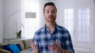 A man dressed in a plaid shirt stands in a living room, emphasizing the importance of learning from slip-ups and mistakes.