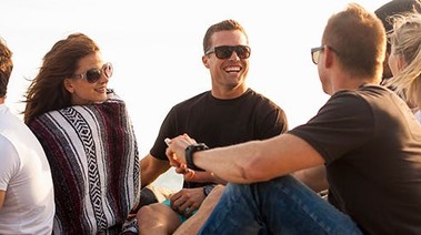 A cheerful group sitting on the beach, surrounded by sand and the soothing sounds of the ocean.