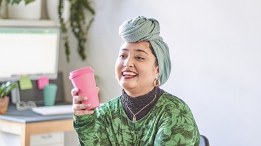 A woman in a turban holds a pink cup, symbolizing relaxation in her smoke-free journey.