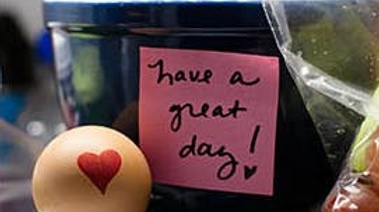 A cup of yellow balls with one beside it, featuring a heart. A sticky note on the cup says, "Have a great day."